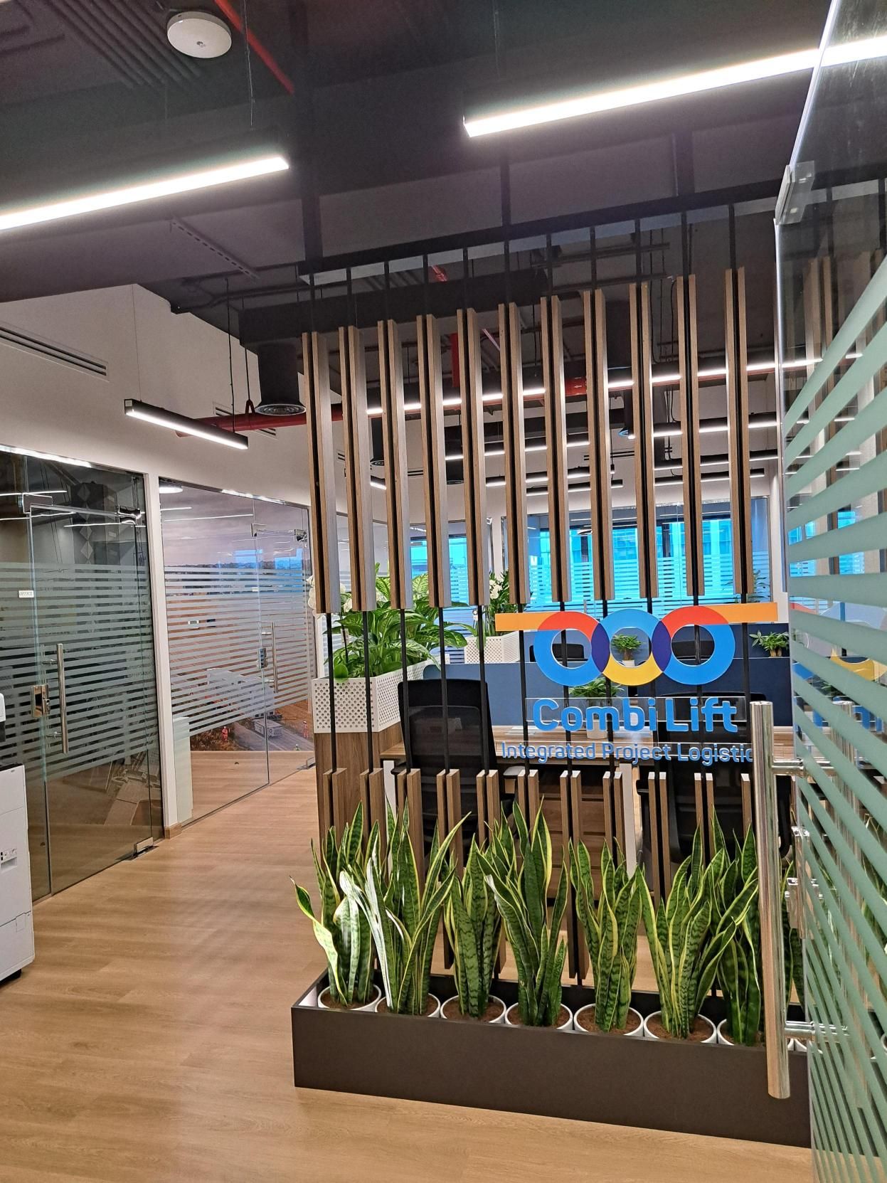 Reception entrance area with Combi Lift logo, wood slats, and potted plants in a modern office setting.